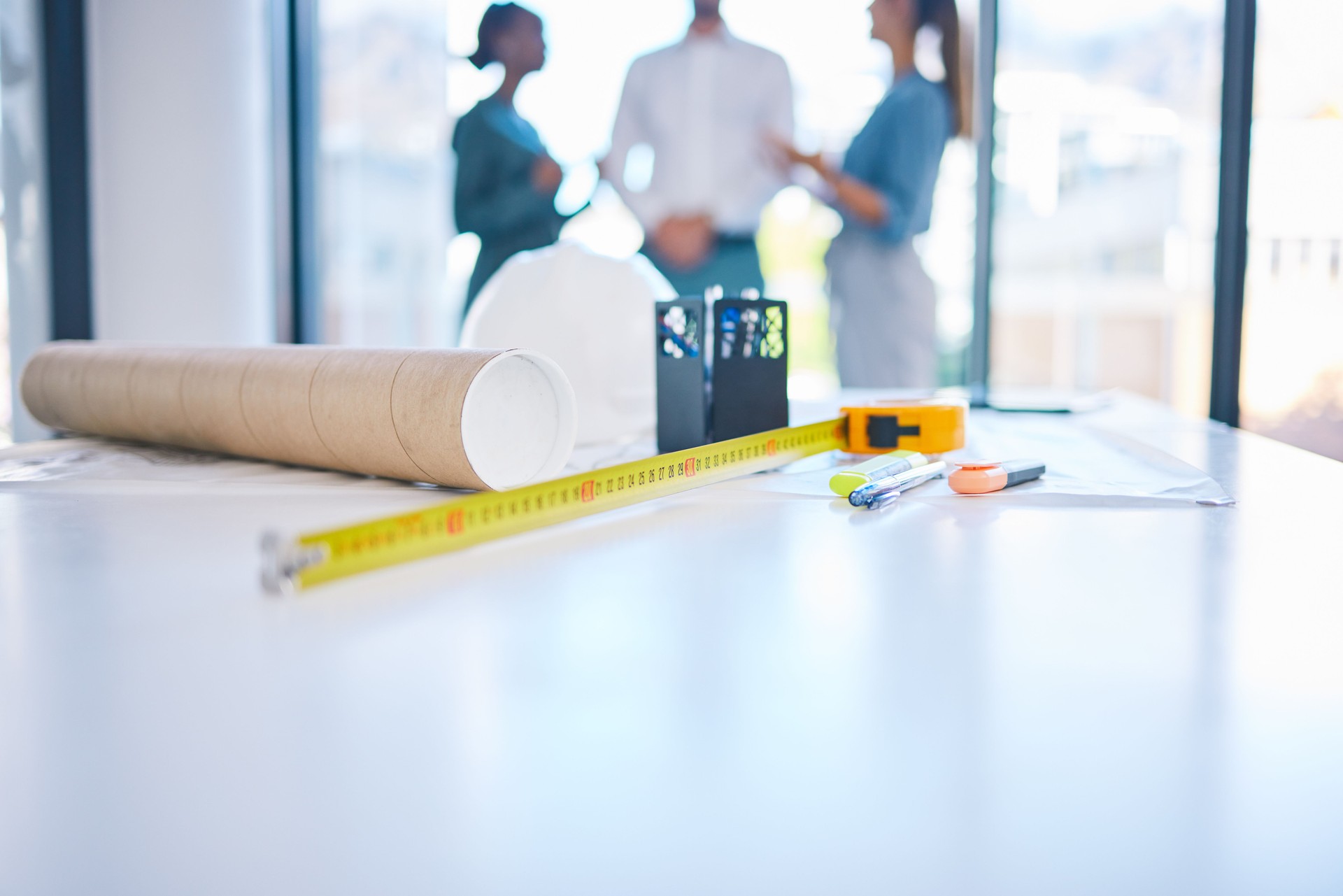 Architecture, construction and building with plans, blueprints and tape measure on a desk in an architect office. Closeup of engineer or contractor equipment on a table ready for planning and design